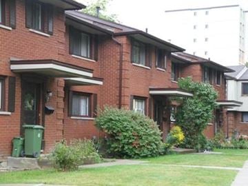 Hamilton apartment for rent - A red brick building with green bushes in front.