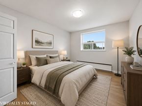 Hamilton apartment for rent - A bedroom with a large bed and a window overlooking a tree-lined landscape.