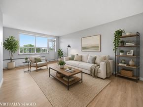 Hamilton apartment for rent - A living room with a white couch, a coffee table, and a large window.