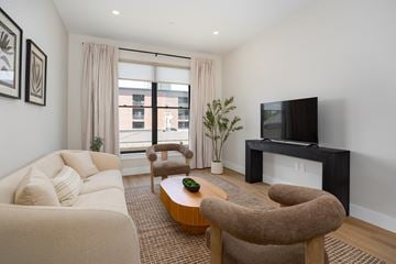 Beacon apartment for rent - A living room with a white couch, a brown chair, and a television.