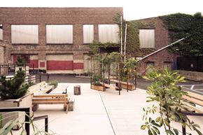 Newburgh apartment for rent - A courtyard with benches and plants in front of a brick building.