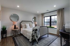 Poughkeepsie apartment for rent - A bedroom with a bed, a side table with a lamp, and a window with a view of trees.