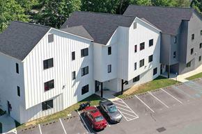 Poughkeepsie apartment for rent - A red car is parked in a parking lot in front of a white building.