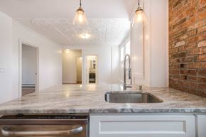 Beacon apartment for rent - A kitchen with a marble countertop and a brick wall.