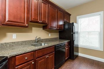 Poughkeepsie apartment for rent - A kitchen with brown cabinets and black appliances.