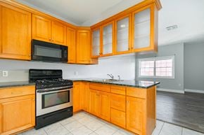 Poughkeepsie apartment for rent - A kitchen with wooden cabinets and black appliances.