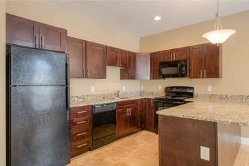 Poughkeepsie apartment for rent - A kitchen with brown cabinets and a black refrigerator.