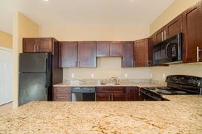Poughkeepsie apartment for rent - A kitchen with black appliances and wooden cabinets.