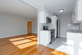 Poughkeepsie apartment for rent - A kitchen with white cabinets and appliances, a wooden floor, and a door to another room.