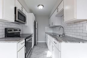 Poughkeepsie apartment for rent - A kitchen with white cabinets and a black and white tiled backsplash.