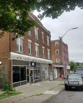 Poughkeepsie apartment for rent - A street view of a brick building with a closed shop in front.