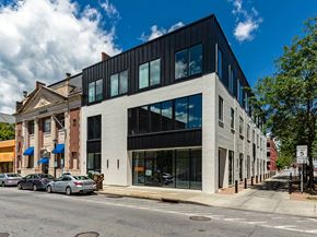 Poughkeepsie apartment for rent - A modern building with a black and white facade is situated on a street corner with cars parked in front.