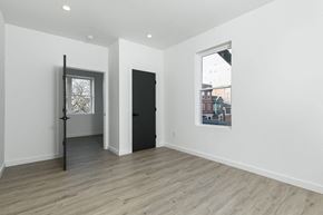 Poughkeepsie apartment for rent - A room with a black door and a window with a view of a building outside.