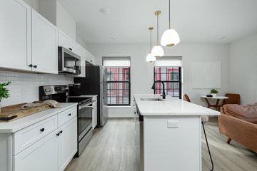 Poughkeepsie apartment for rent - A modern kitchen with white cabinets and a black refrigerator.