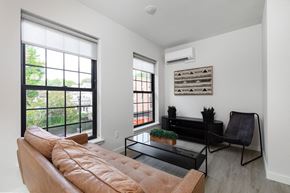 Poughkeepsie apartment for rent - A living room with a brown couch, a black coffee table, and a window with a view of trees.