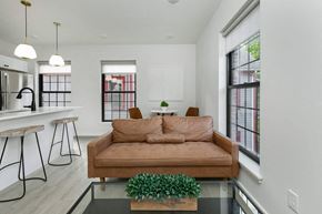 Poughkeepsie apartment for rent - A brown couch is in the middle of a white room with a glass table in front of it.