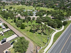 Mcallen apartment for rent - A road runs through a green park with palm trees.
