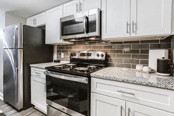 A kitchen with a black stove top oven and a black microwave above it.