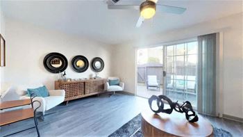 A living room with a white sofa, a wooden coffee table, and a ceiling fan.