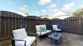 A patio with a white chair and a black table.