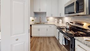 Peachtree Corners apartment for rent - A modern kitchen with white cabinets and a black stove top.