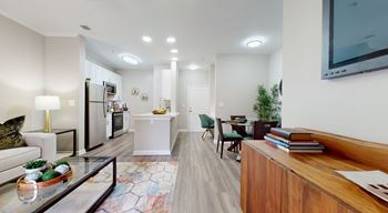 A modern living room with a glass coffee table and a wooden bookshelf.