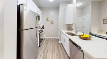 A kitchen with white cabinets and a stainless steel refrigerator.