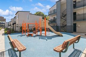 Oakland apartment for rent - A playground with a slide and swings in front of a building at Oak Center Apartments, Oakland, California