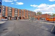 Chicago apartment for rent - A parking lot in front of a multi-story brick building at Fullerton Court Apartments, Chicago