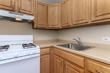 Chicago apartment for rent - A white gas stove is in a kitchen with wooden cabinets.