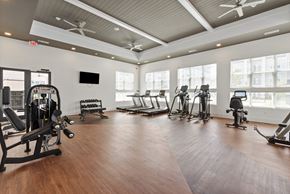 Charlotte apartment for rent - A gym with a variety of equipment including treadmills, weights, and a television.
