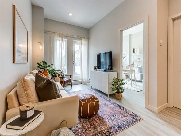 Edmonton apartment for rent - A living room with a beige couch, a small table with a book and a candle, a television, and a rug with a pattern.