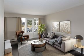 Prince George apartment for rent - A living room with a grey couch, a brown armchair, a coffee table, and a floor lamp.