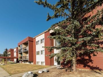 Prince George apartment for rent - A red and white building with a tree in front.