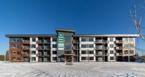 Prince George apartment for rent - A large building with a sign that says "Your Home Awaits" in front of it.