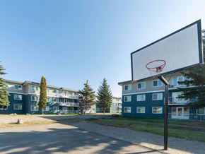 Prince George apartment for rent - A basketball hoop is in the foreground of a residential area with apartment buildings in the background.