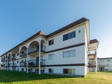 Prince George apartment for rent - A white and brown building with balconies and a red roof.