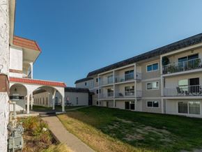 Prince George apartment for rent - A building with a red roof and a white building with a balcony.