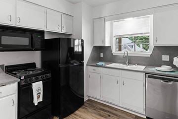 Carlsbad apartment for rent - A black stove and refrigerator in a kitchen with white cabinets.