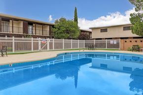 Carlsbad apartment for rent - A swimming pool in front of a building with a fence around it.