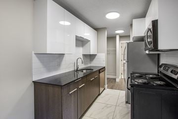 Edmonton apartment for rent - A modern kitchen with dark wood cabinets and a black stove top oven.