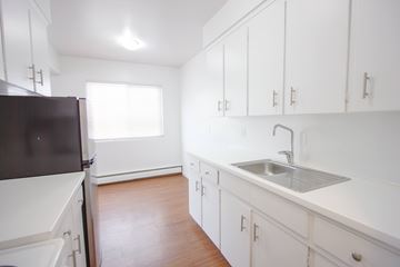 Edmonton apartment for rent - A kitchen with white cabinets and a black refrigerator.