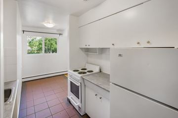 Edmonton apartment for rent - A kitchen with white cabinets and a stove top oven.