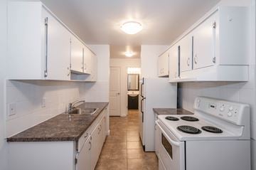 Edmonton apartment for rent - A kitchen with white cabinets and a white stove top oven.