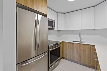 Edmonton apartment for rent - A modern kitchen with a stainless steel refrigerator and wooden cabinets.