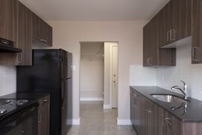 Edmonton apartment for rent - A kitchen with black appliances and brown cabinets.