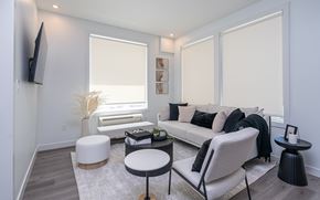 Edmonton apartment for rent - A living room with a white couch, a white ottoman, and a black chair.