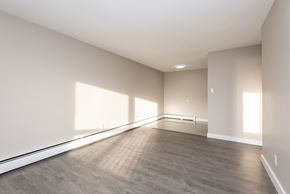 Edmonton apartment for rent - A large empty room with wooden flooring and white walls.