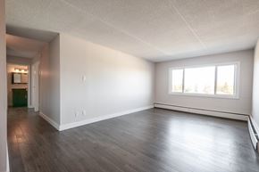 Edmonton apartment for rent - A spacious room with wooden flooring and a window.