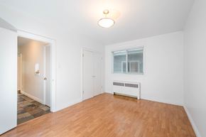Edmonton apartment for rent - A room with a wooden floor and a window with blinds.